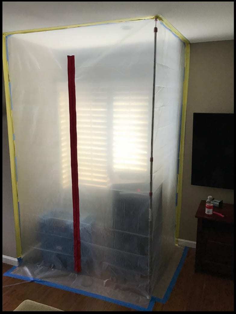 Plastic containment chamber with a zipper door set up in a living room