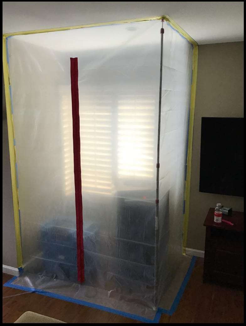 Plastic containment chamber with a zipper door set up in a living room