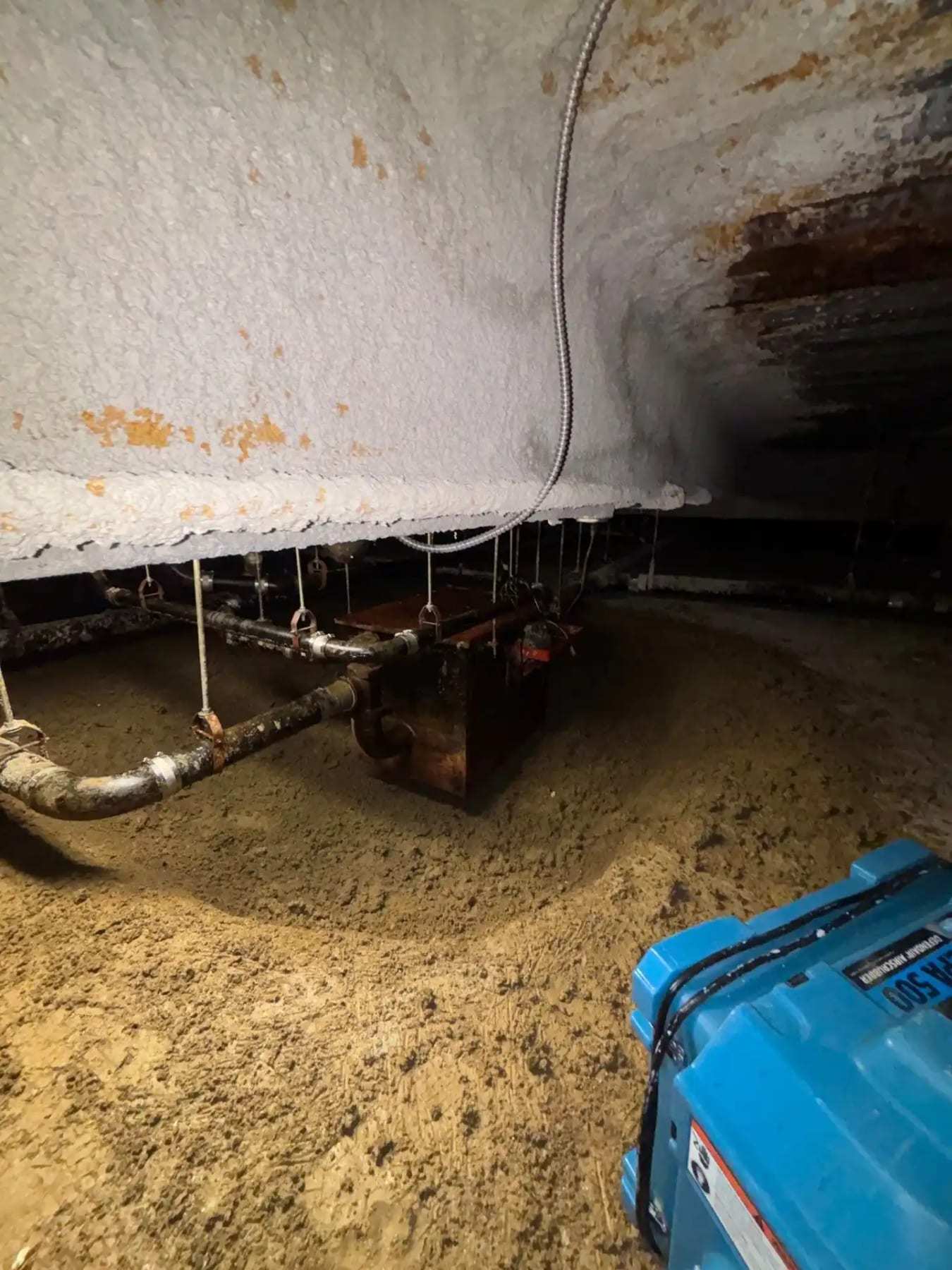 Dehumidifier in a dirt crawlspace below exposed pipes